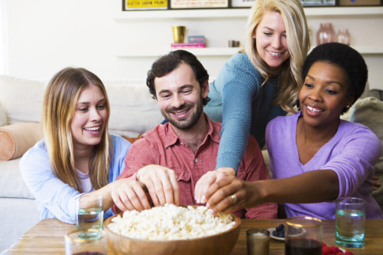 Diverse group of friends happily sharing a bowl of popcorn