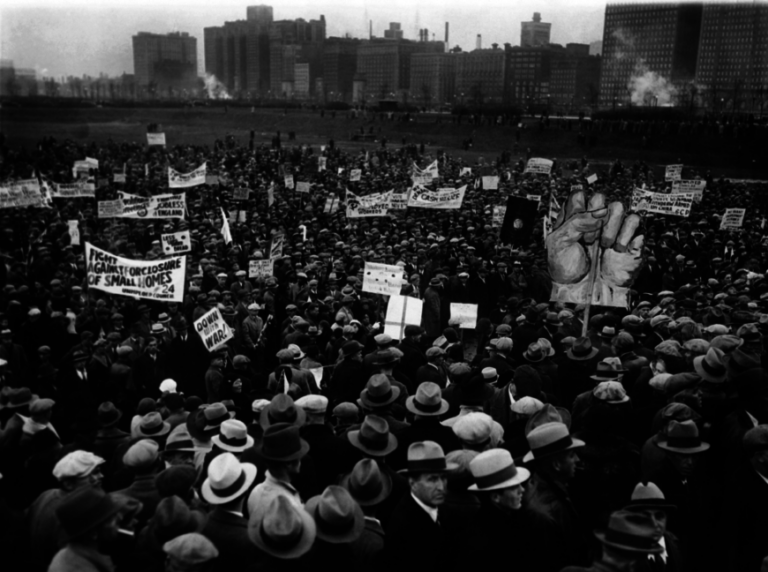 Dated black and white photo of a large protest in urban setting