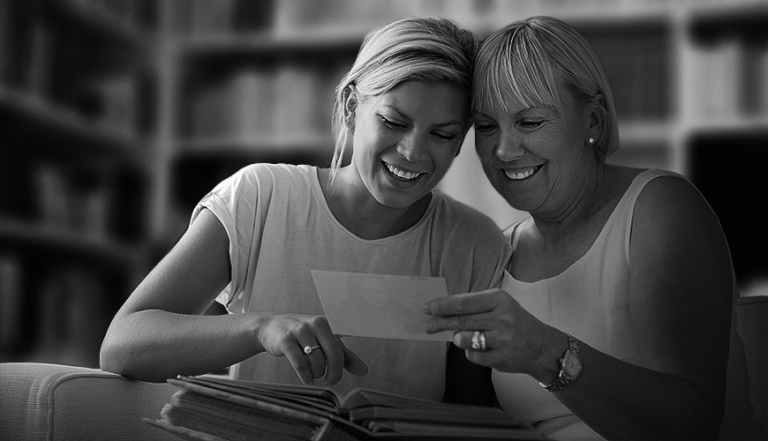 Smiling mother and adult daughter looking at photos together