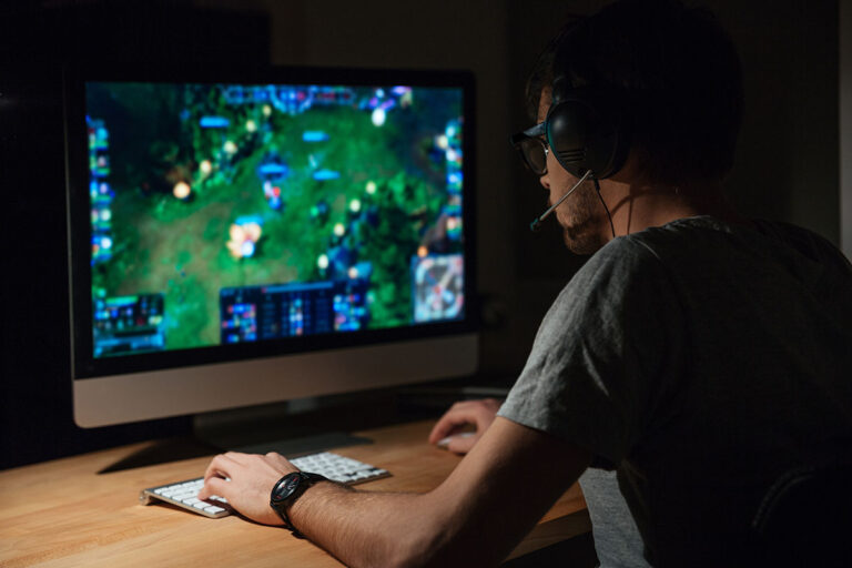 Concentrated gamer in headphones using computer for playing game