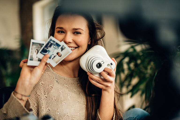 Millennial holding a camera and a few photos