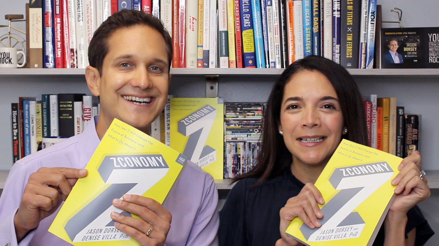 Authors Jason Dorsey and Denise Villa, PhD, holding copies of their book Zconomy and smiling