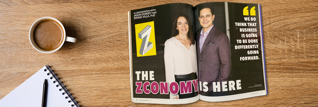 Desktop with an open magazine featuring Jason and Denise and their new book Zconomy.